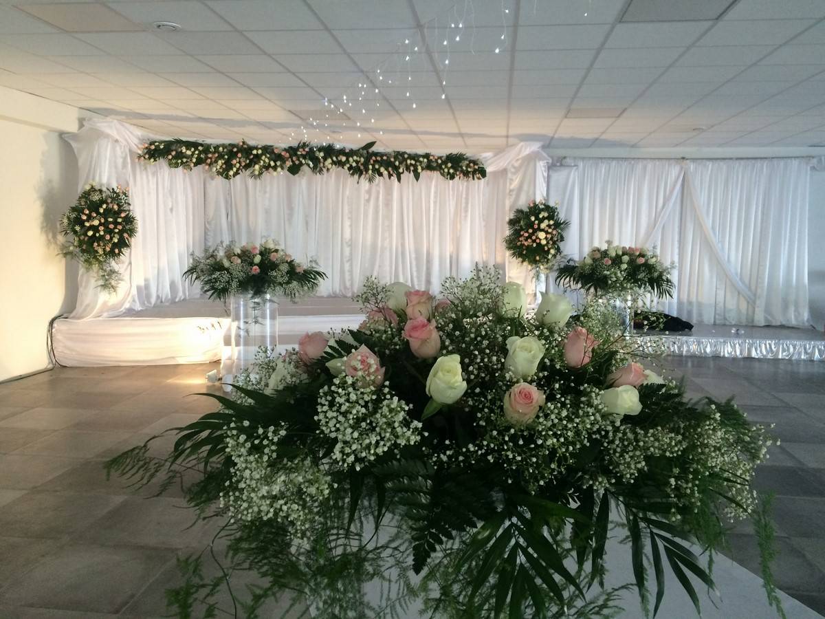 Les taches de fleurs de roses sont judicieusement installées à hauteur des invités pour cette grande salle.