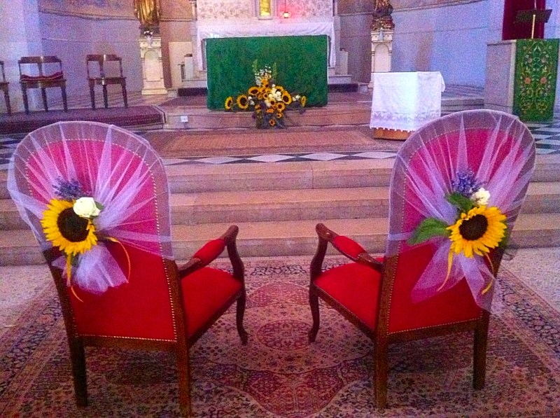 les fauteuils des mariés pour la cérémonie sont habillés de tulle blanc et de fleurs