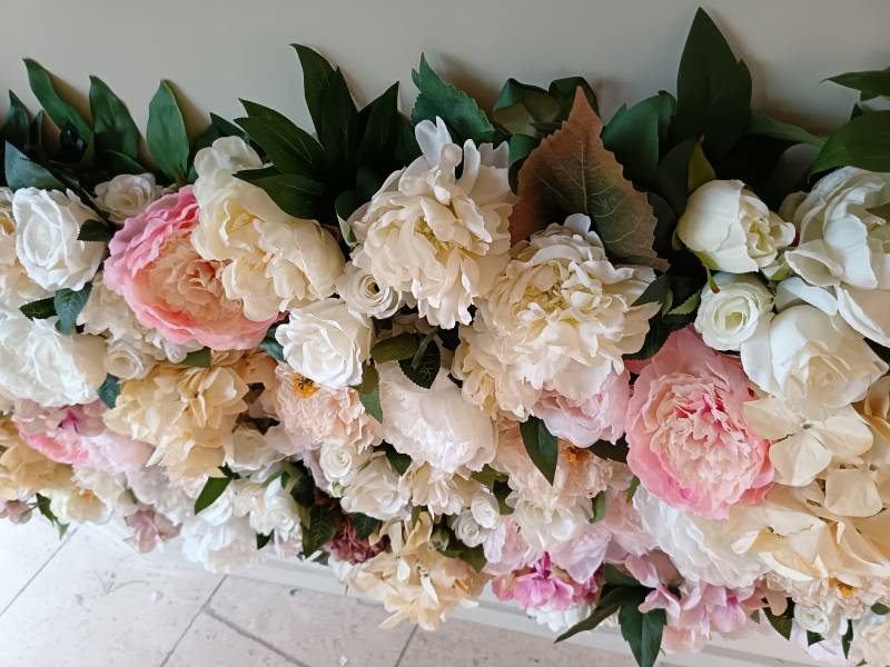 Les fleurs de pivoines se marient à merveille avec les roses et les hortensias dans ce beau mur floral.