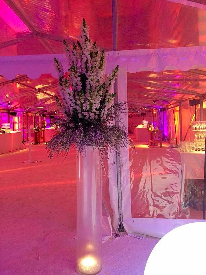 Le bouquet de fleurs blanches est surmonté d'un vase tube en verre et d'une lumière leds blanche dans des billes d'eau en gel.