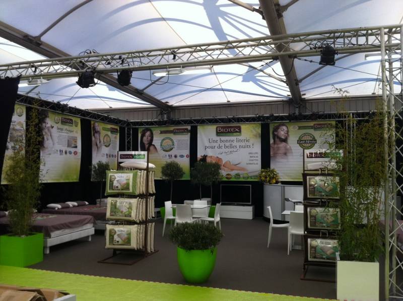 Le stand du salon à Avignon est décoré ici avec des oliviers en boule dans des jolis pots en résines blanches et vert anis.